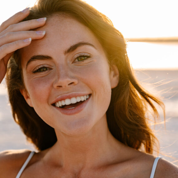 Image of a happy young pretty girl walking outdoors at the beach